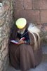 un religieux en pleine lecture à l'ombre d'une église